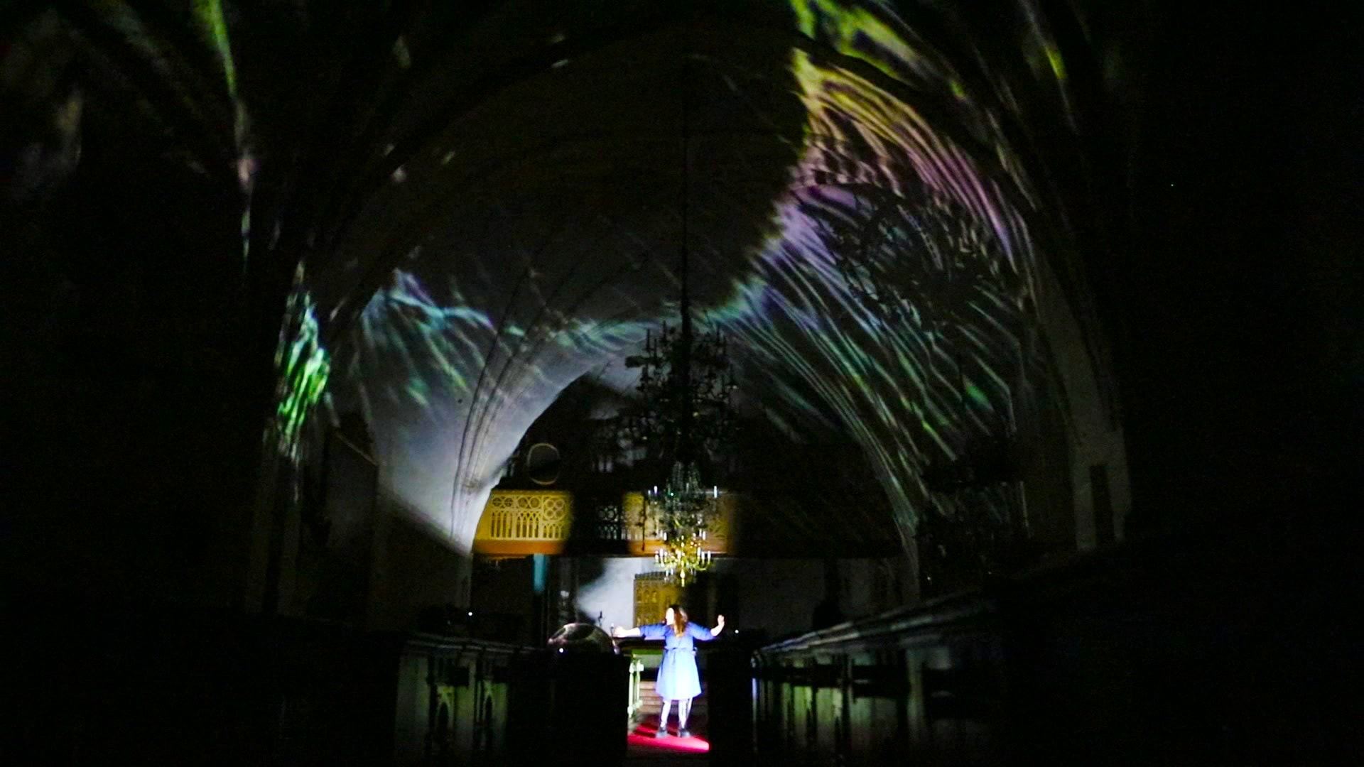 Wave projection sweeping across the vault, the singer alone in the aisle