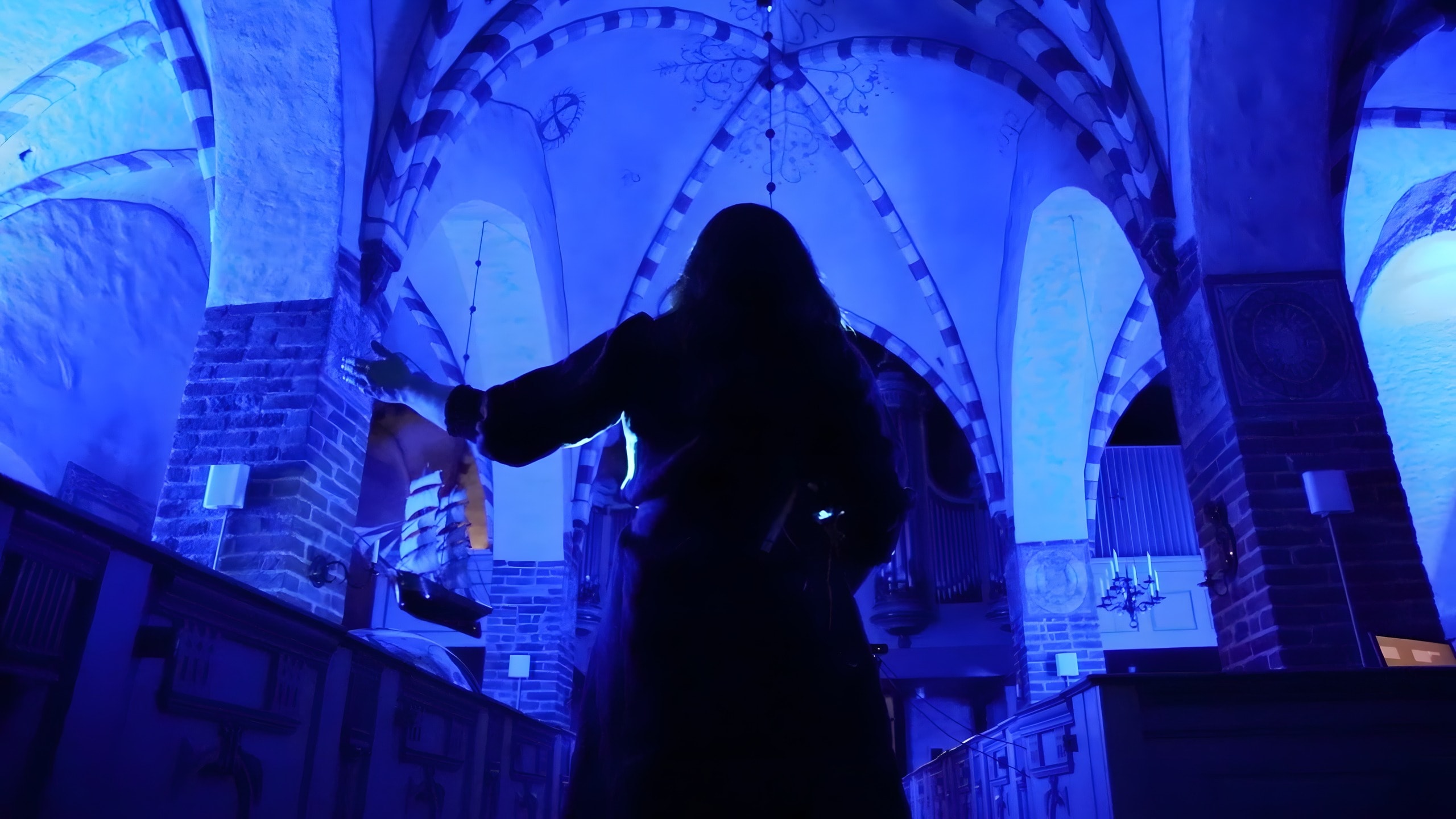 Aqua — the singer in silhouette beneath the blue-lit vaults of an archipelago church