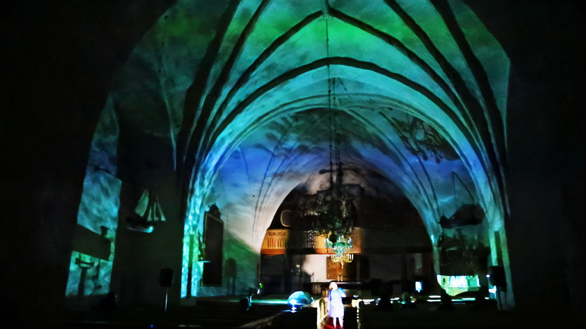 Aqua — projected water flowing across the medieval vaults of Nagu church, the singer at the altar