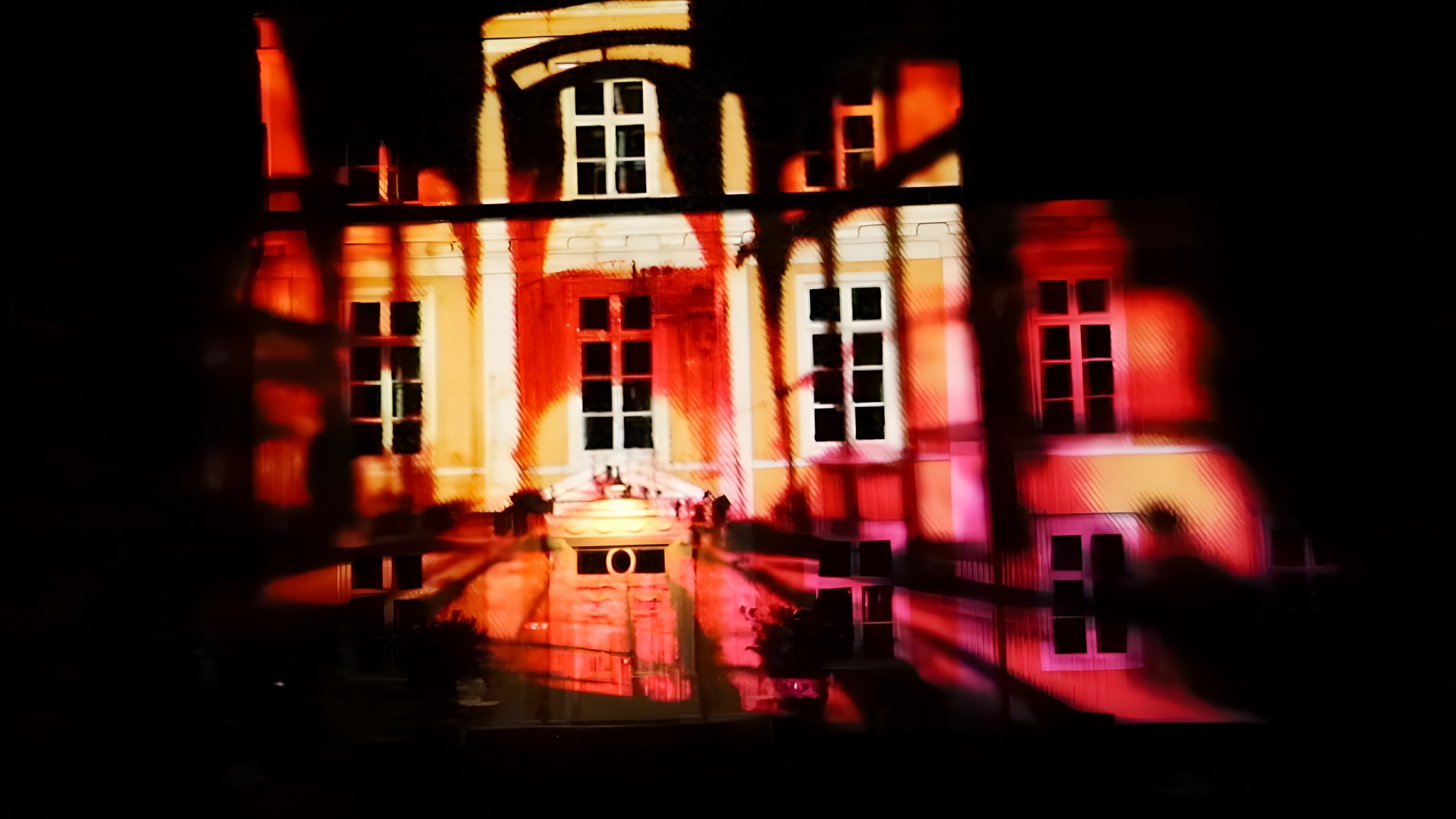 Masuuni — the façade of Mustio Manor glowing in furnace reds and oranges
